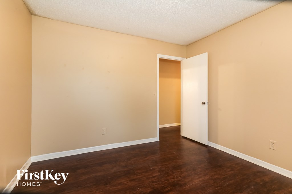 a empty living room with wood floors and a door to a closet