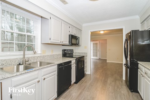 A kitchen with black appliances and white cabinets.