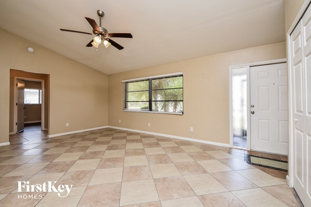 an empty living room with a ceiling fan and a window