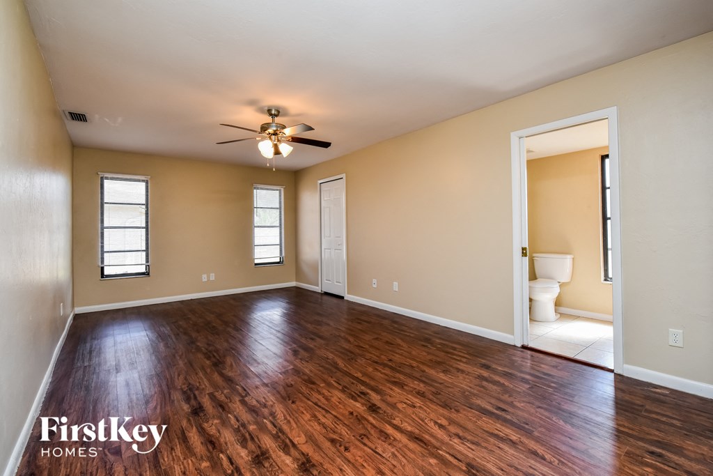 an empty living room with wood flooring and a ceiling fan