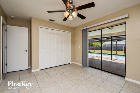 a room with a ceiling fan and a door to a pool