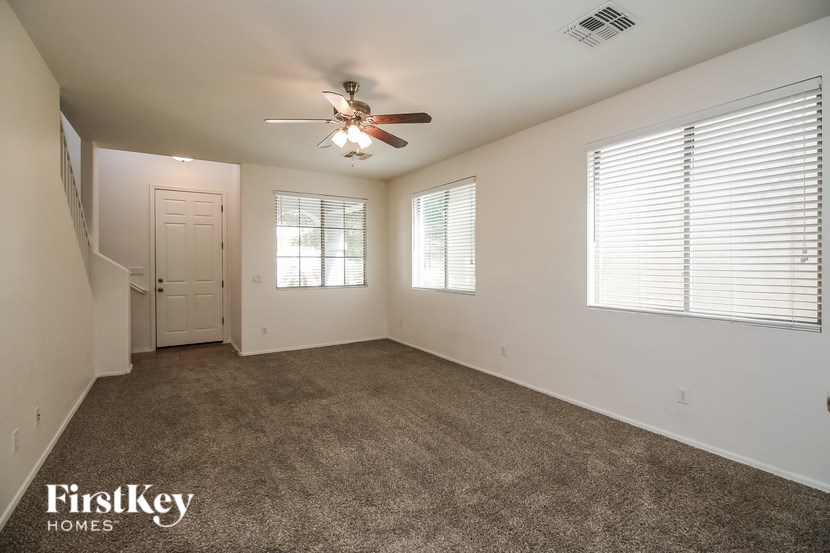 A spacious room with a ceiling fan and carpeted floor.