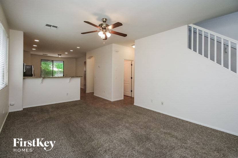 A spacious room with a ceiling fan and a carpeted floor.