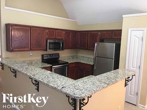 A kitchen with a granite counter top and wooden cabinets.