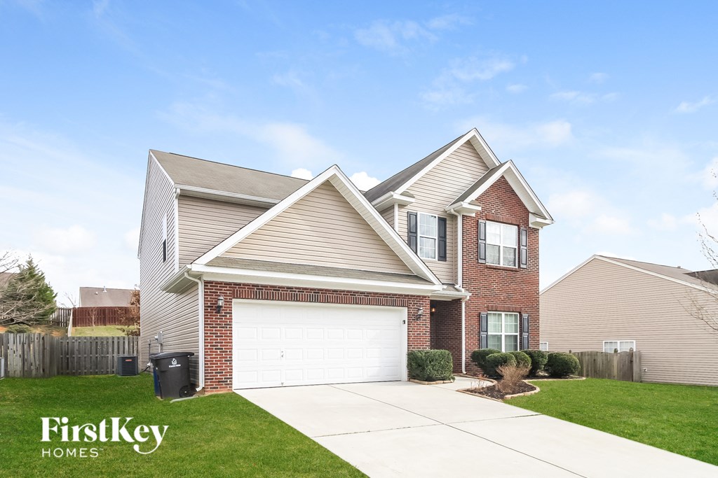 a brick house with a white garage door in front of a lawn