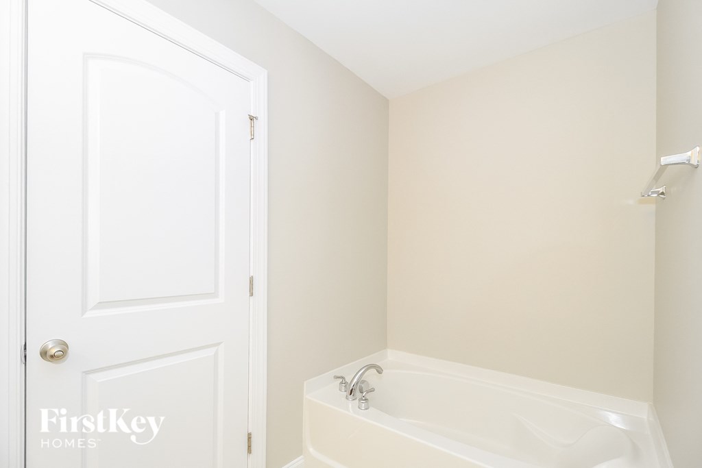 a bathroom with a white bath tub and a white door