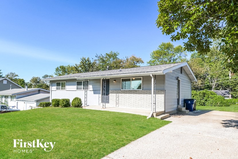 a small white house with a driveway and lawn
