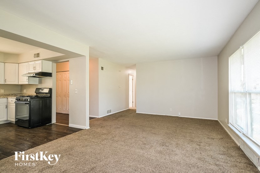 an empty living room and kitchen with a large window