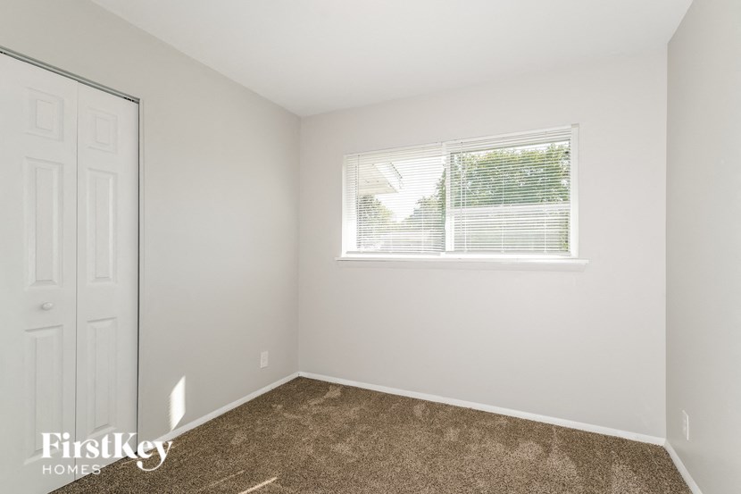 a bedroom with a window and carpeted floor