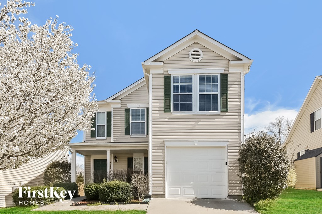 a tan house with a white flowering tree in front of it