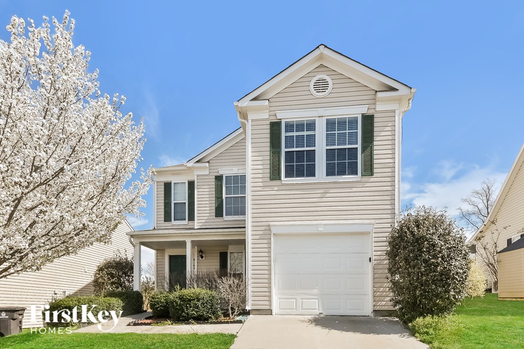 a beige house with a white flowering tree in front of it