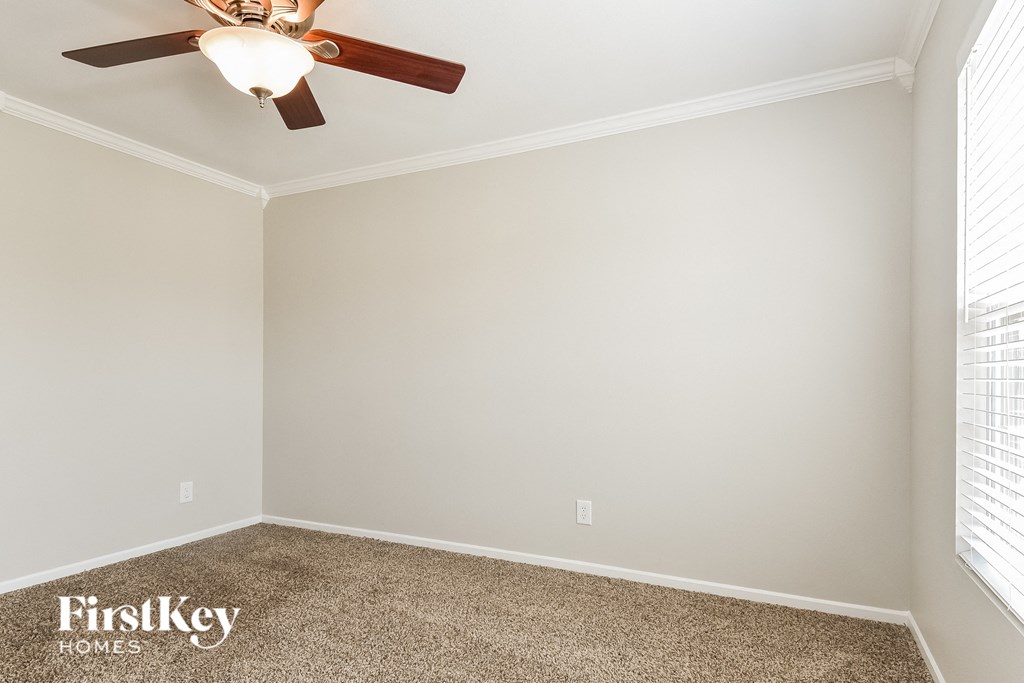 a bedroom with a ceiling fan and a carpet