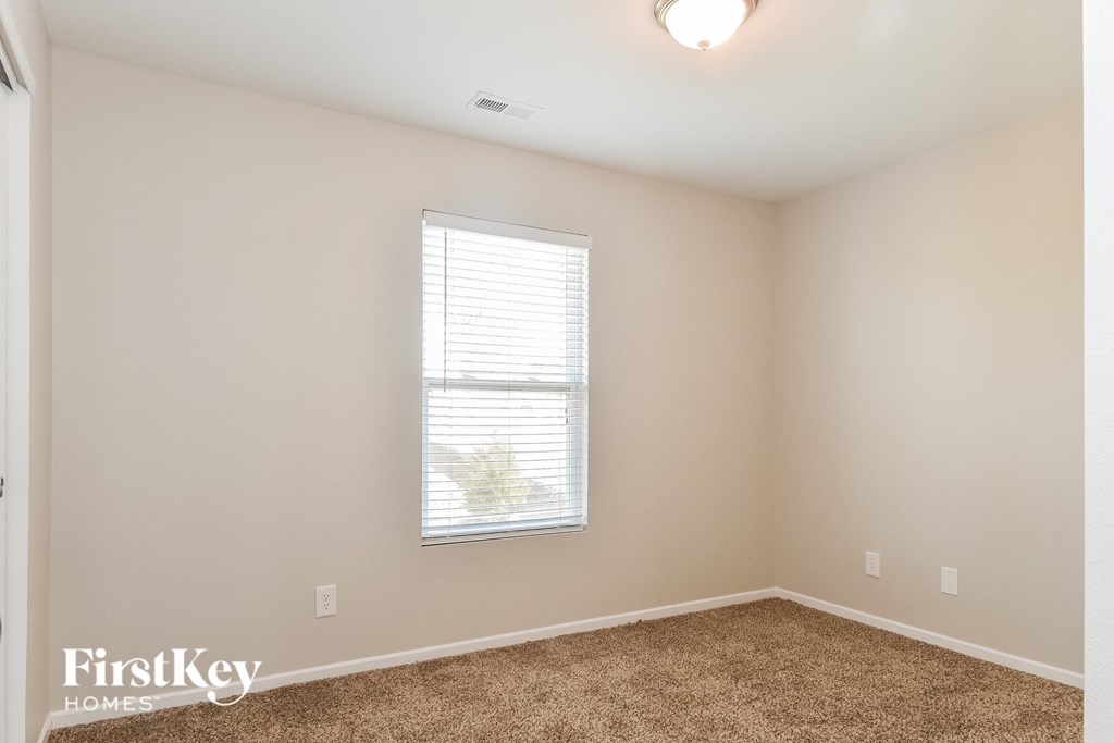 a spacious bedroom with carpet and a window