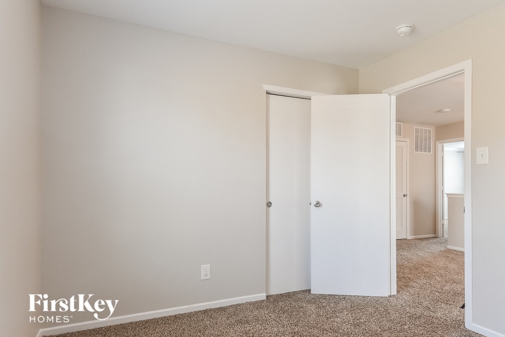 a bedroom with white walls and a closet and a white door