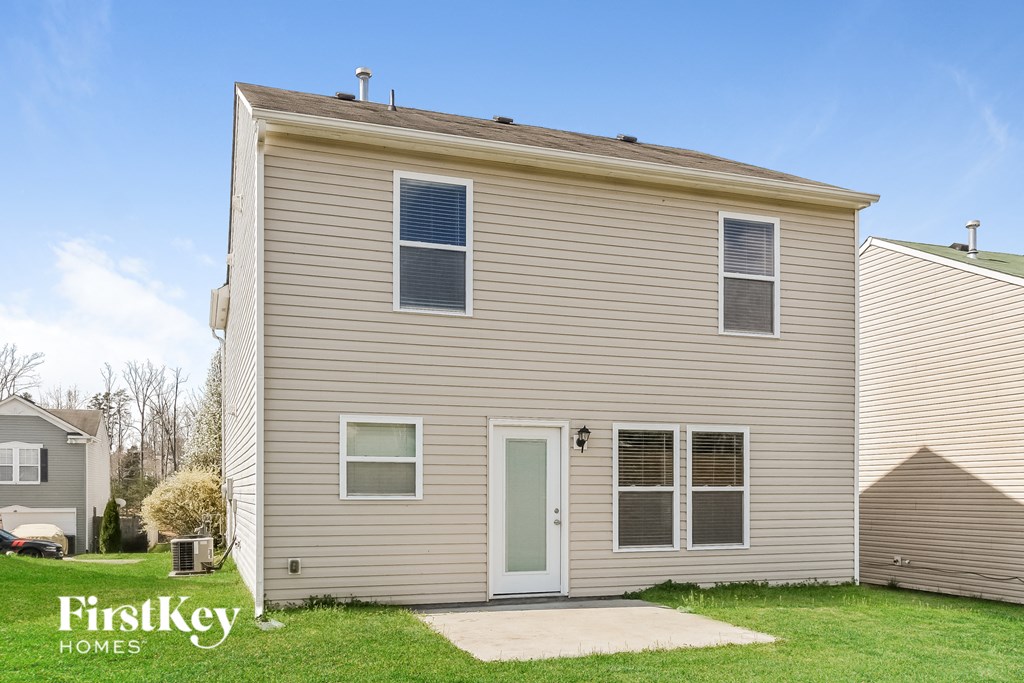 front view of a tan house with white siding and a green door