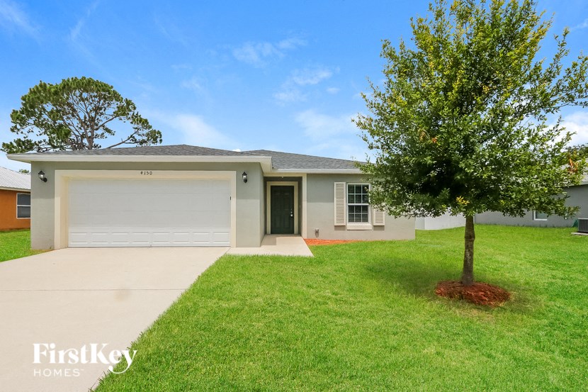 a white house with a lawn and a tree