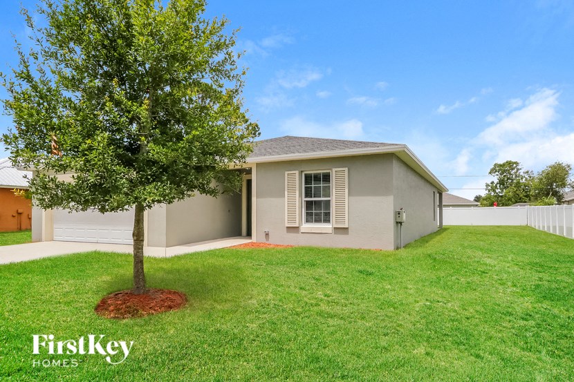 a beige house with a tree in the grass