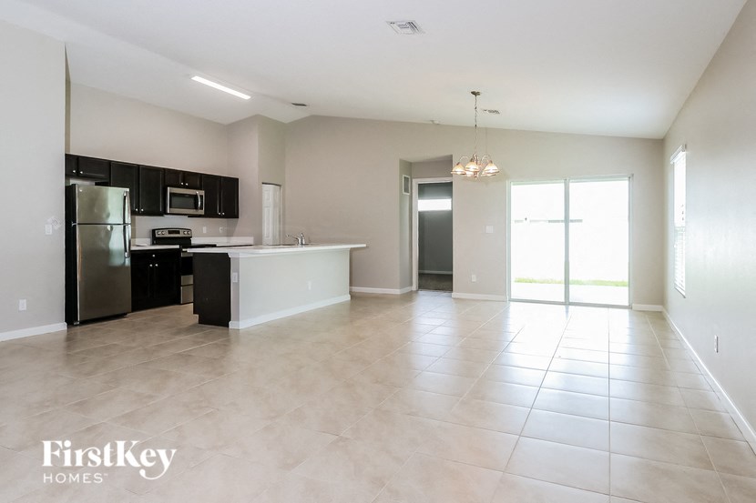 an empty kitchen and living room with a stainless steel refrigerator