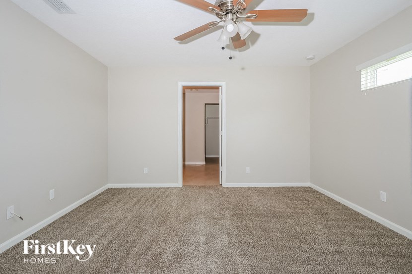 a empty living room with a ceiling fan and carpet