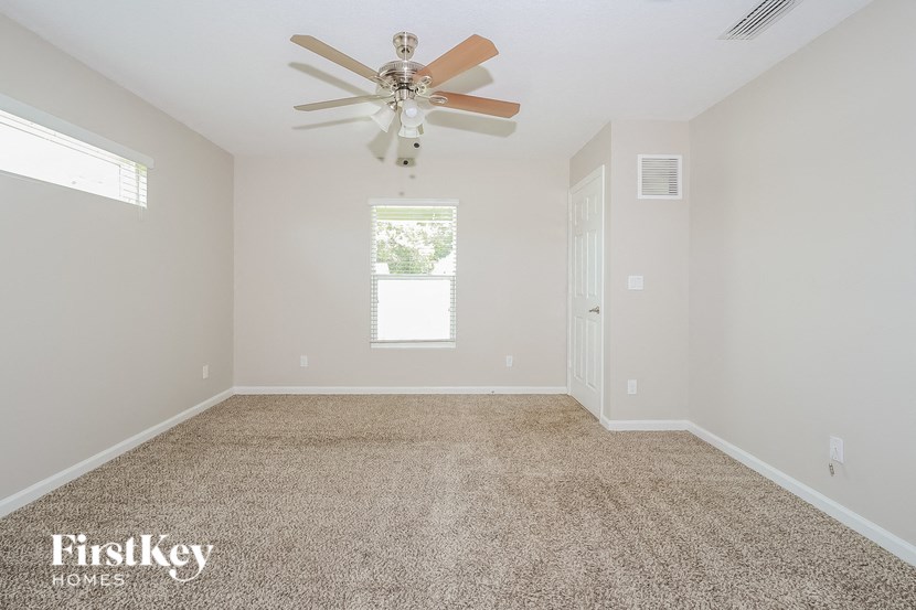 a empty living room with a ceiling fan and carpet