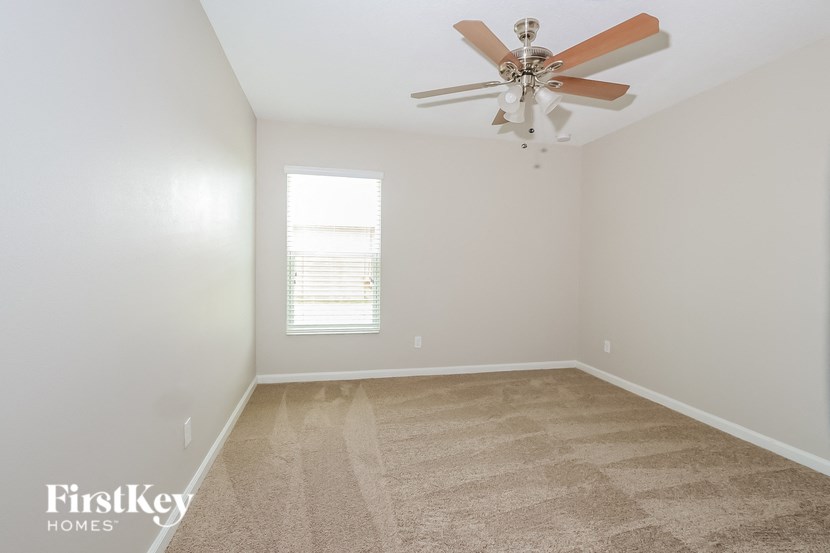 an empty room with a ceiling fan and a window