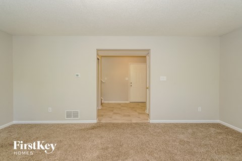A carpeted room with a doorway leading to another room.
