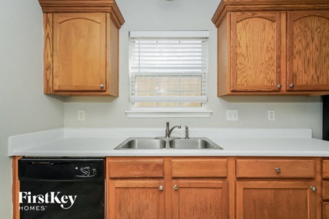 A kitchen with wooden cabinets and a sink under a window.