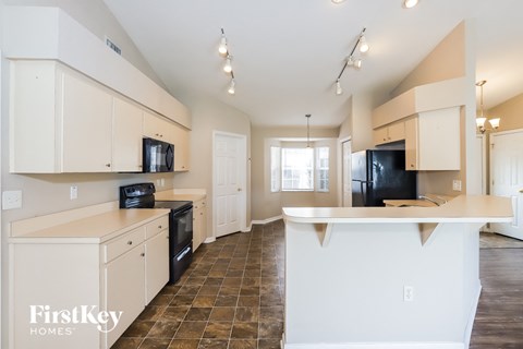 a kitchen with white cabinets and a black refrigerator and a sink