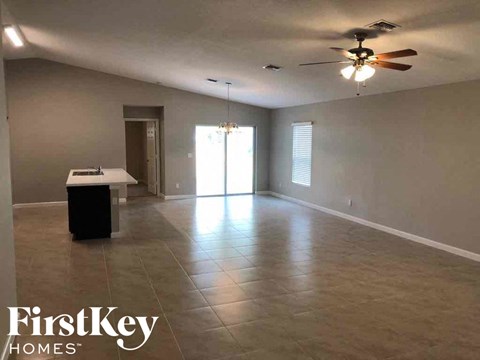 A spacious room with a ceiling fan and a desk.