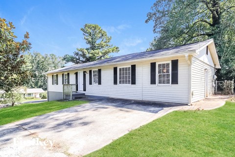 a white house with black shutters and a driveway