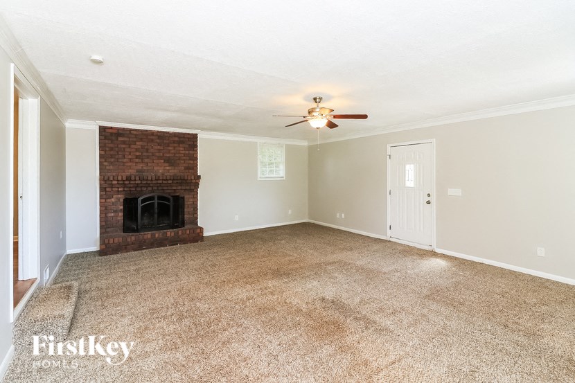 an empty living room with a fireplace and a ceiling fan