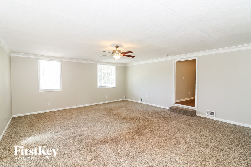 an empty living room with a ceiling fan