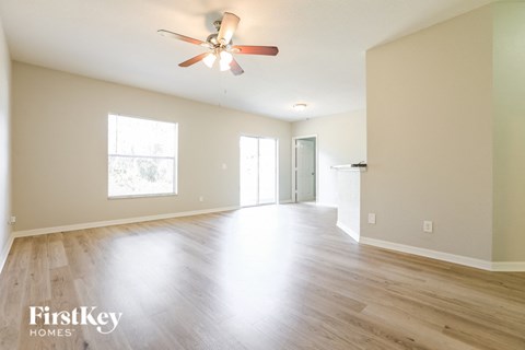 an empty living room with wood floors and a ceiling fan