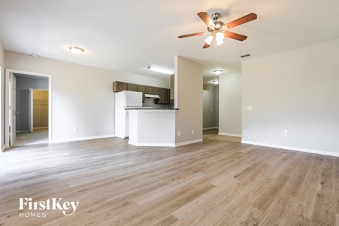 an empty living room with wood flooring and a ceiling fan