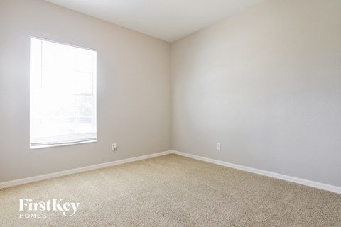 a bedroom with white walls and a window