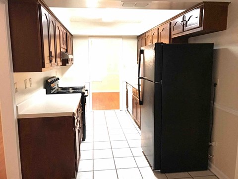 a kitchen with a black refrigerator and cabinets