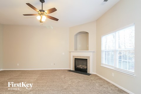 A living room with a fireplace and a ceiling fan.