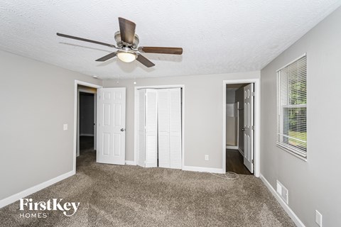 a living room with carpet and a ceiling fan