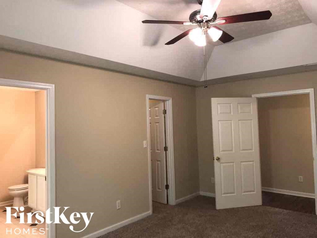 a bedroom with a ceiling fan and a door to the bathroom