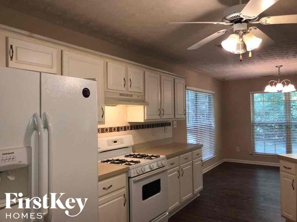 a kitchen with white cabinets and white appliances and a ceiling fan