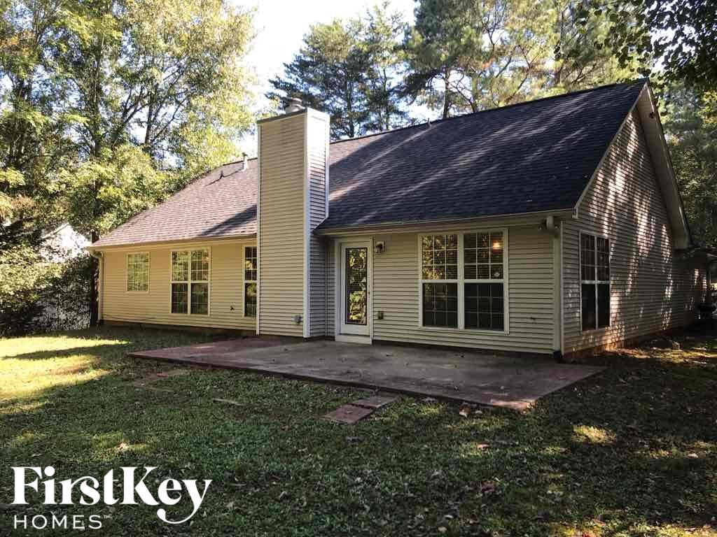 a small yellow house with a porch and a yard