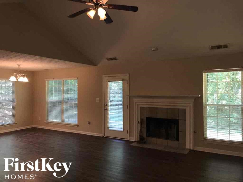 an empty living room with a fireplace and a ceiling fan