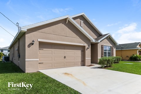 a tan house with a garage and a driveway
