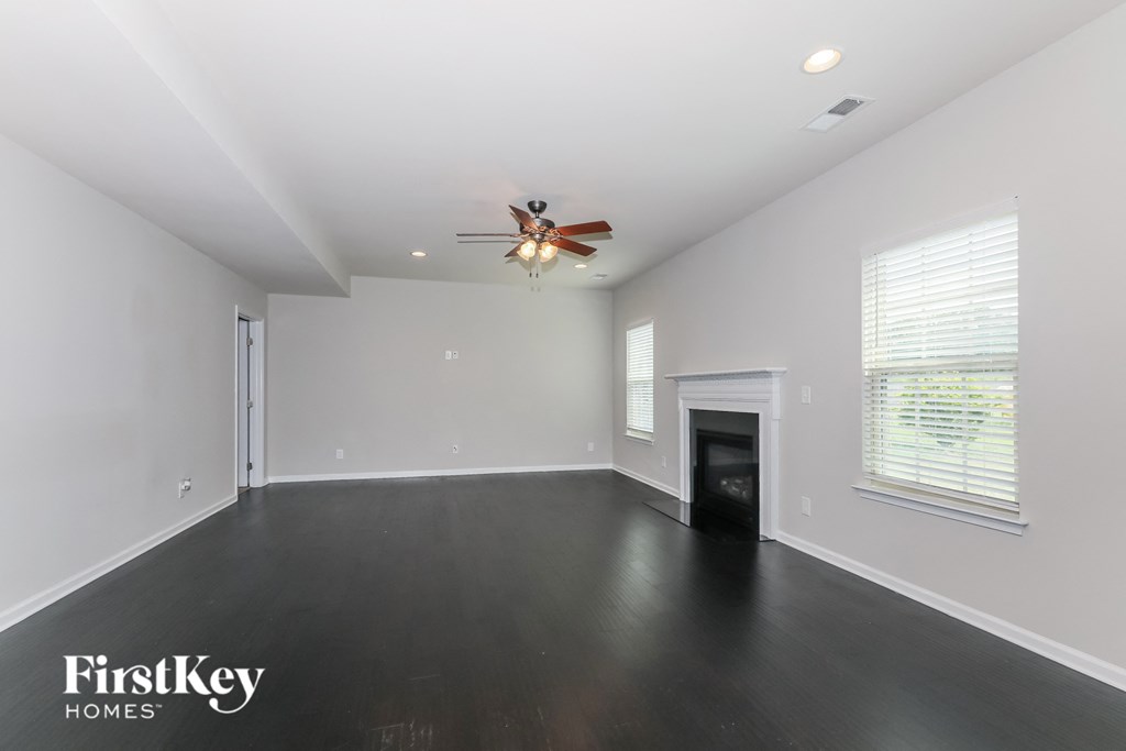 a empty living room with a ceiling fan and a fireplace