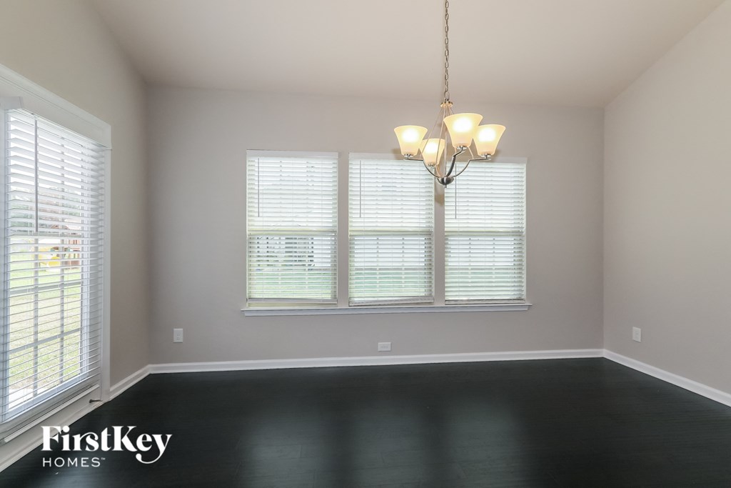 a empty living room with a chandelier and three windows