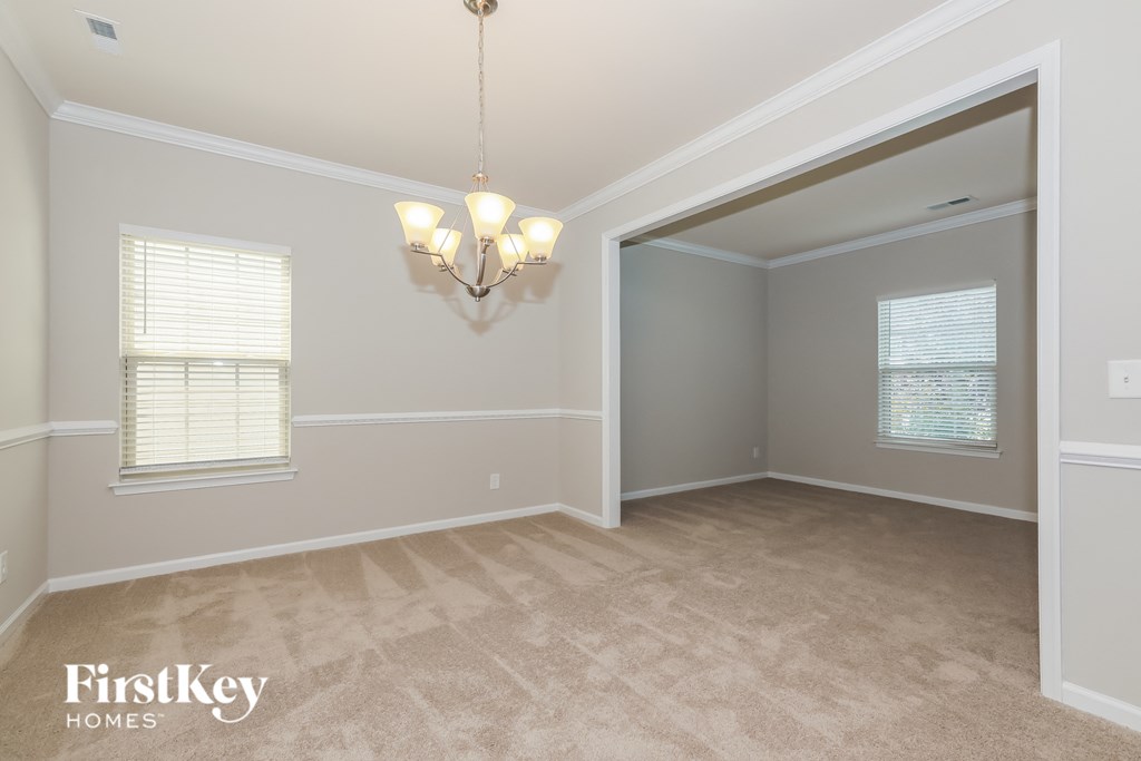 an empty living room with a chandelier and a window