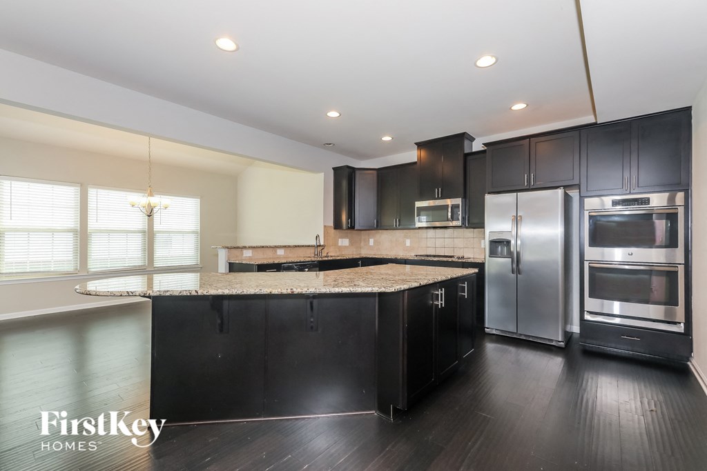 a large kitchen with stainless steel appliances and granite counter tops