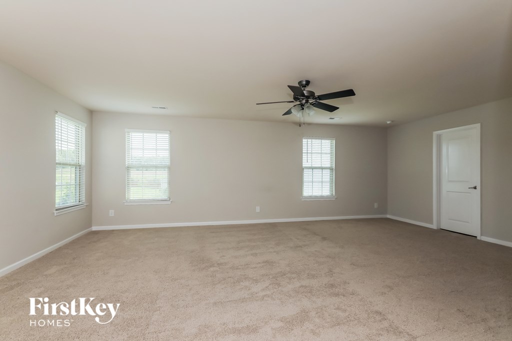 an empty living room with a ceiling fan and a white door