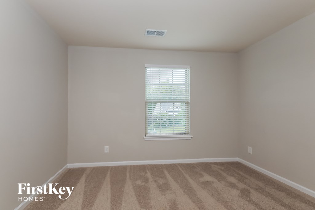 a bedroom with a window and a carpeted floor