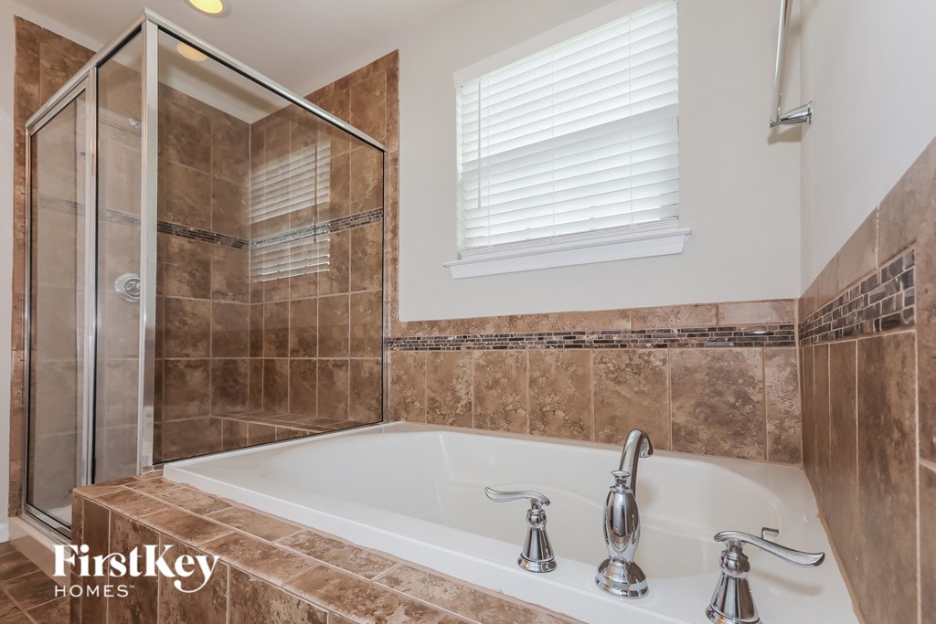 the master bathroom has a large tub and a walk in shower